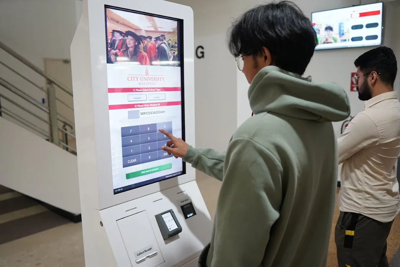 A City University Malaysia student at a self-service registration kiosk on campus